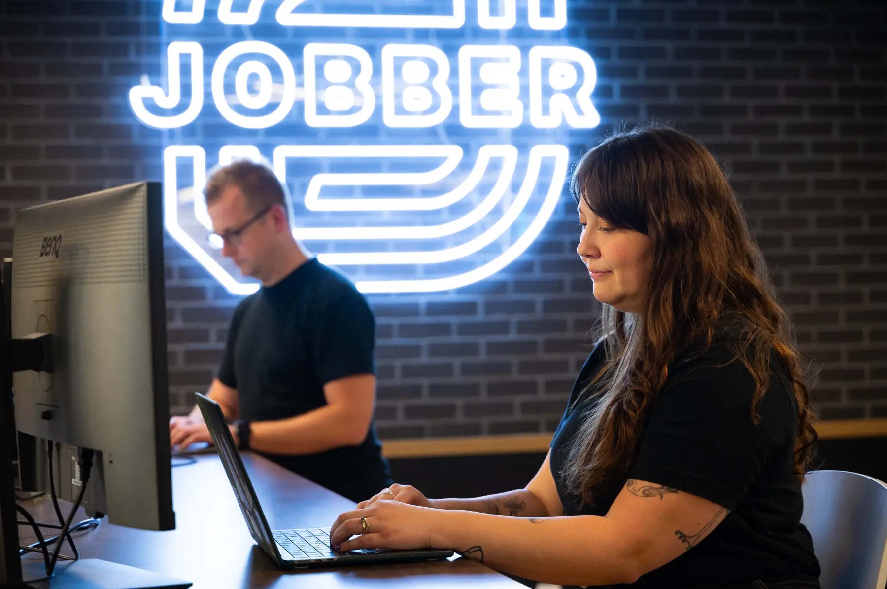 Jobber employees working in the Toronto office in front of our neon sign