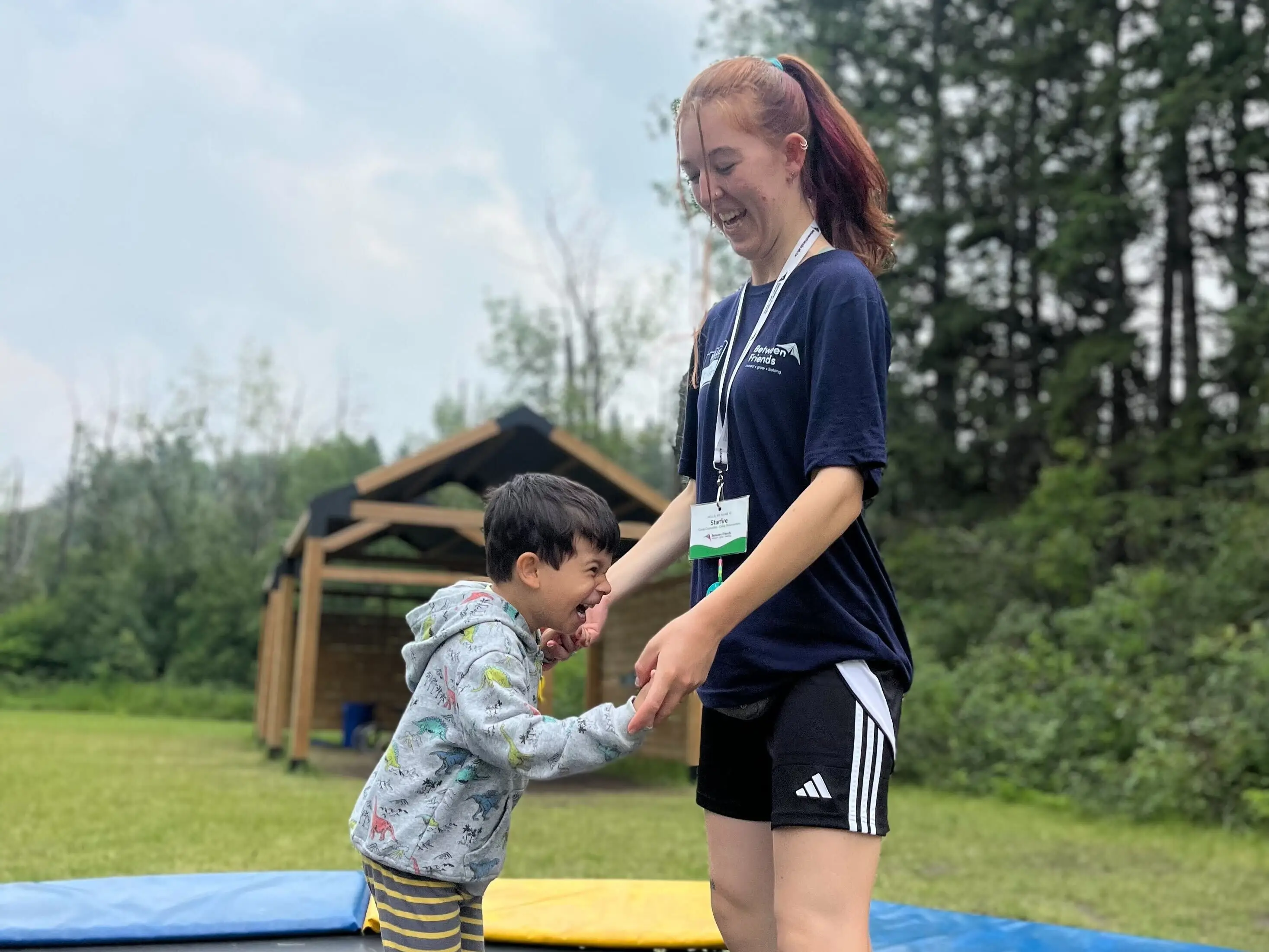 A counsellor and a participant jumping on the in-ground trampoline at Camp Bonaventure
