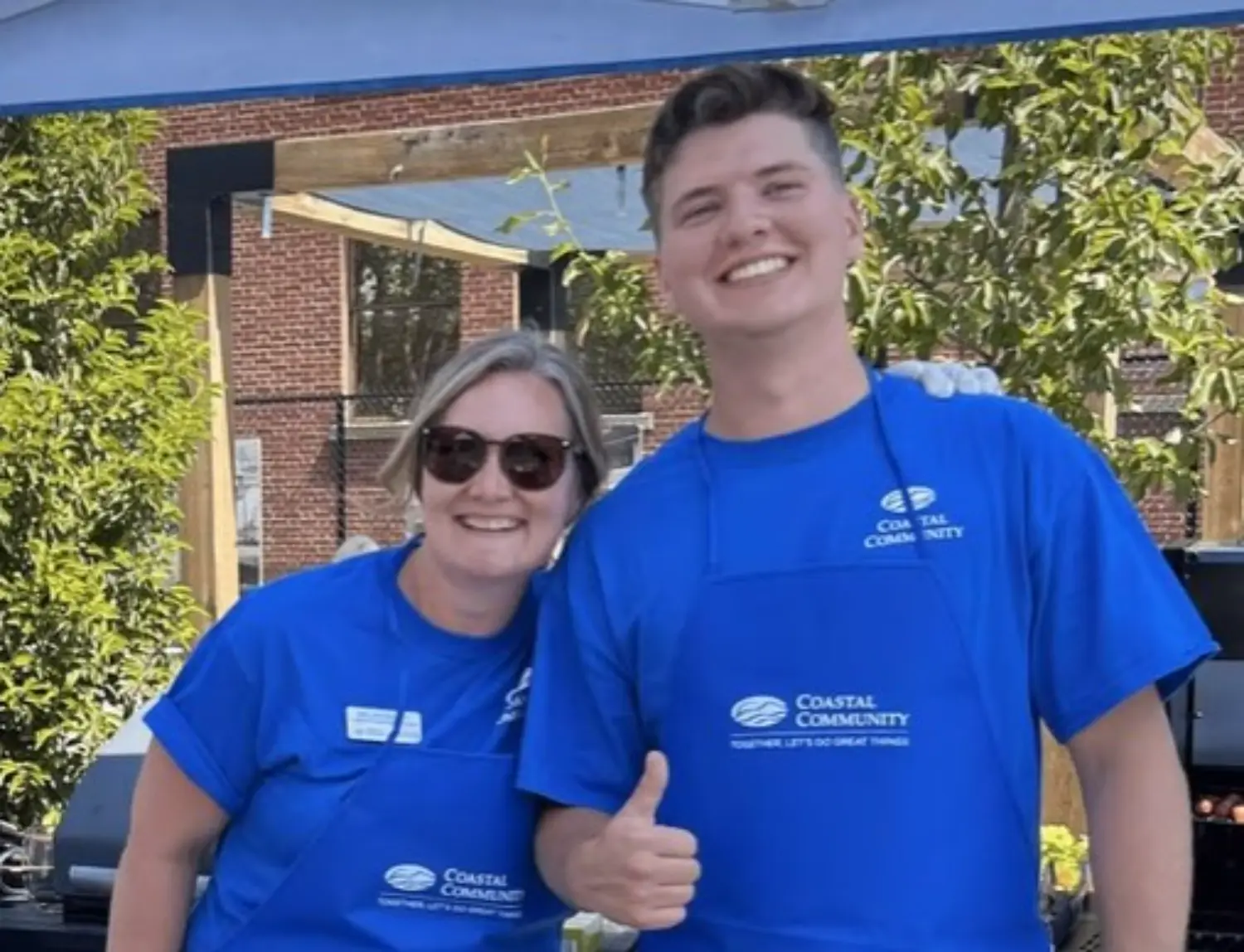 Employees cooking up some burgers and hot dogs at a member & client appreciation BBQ