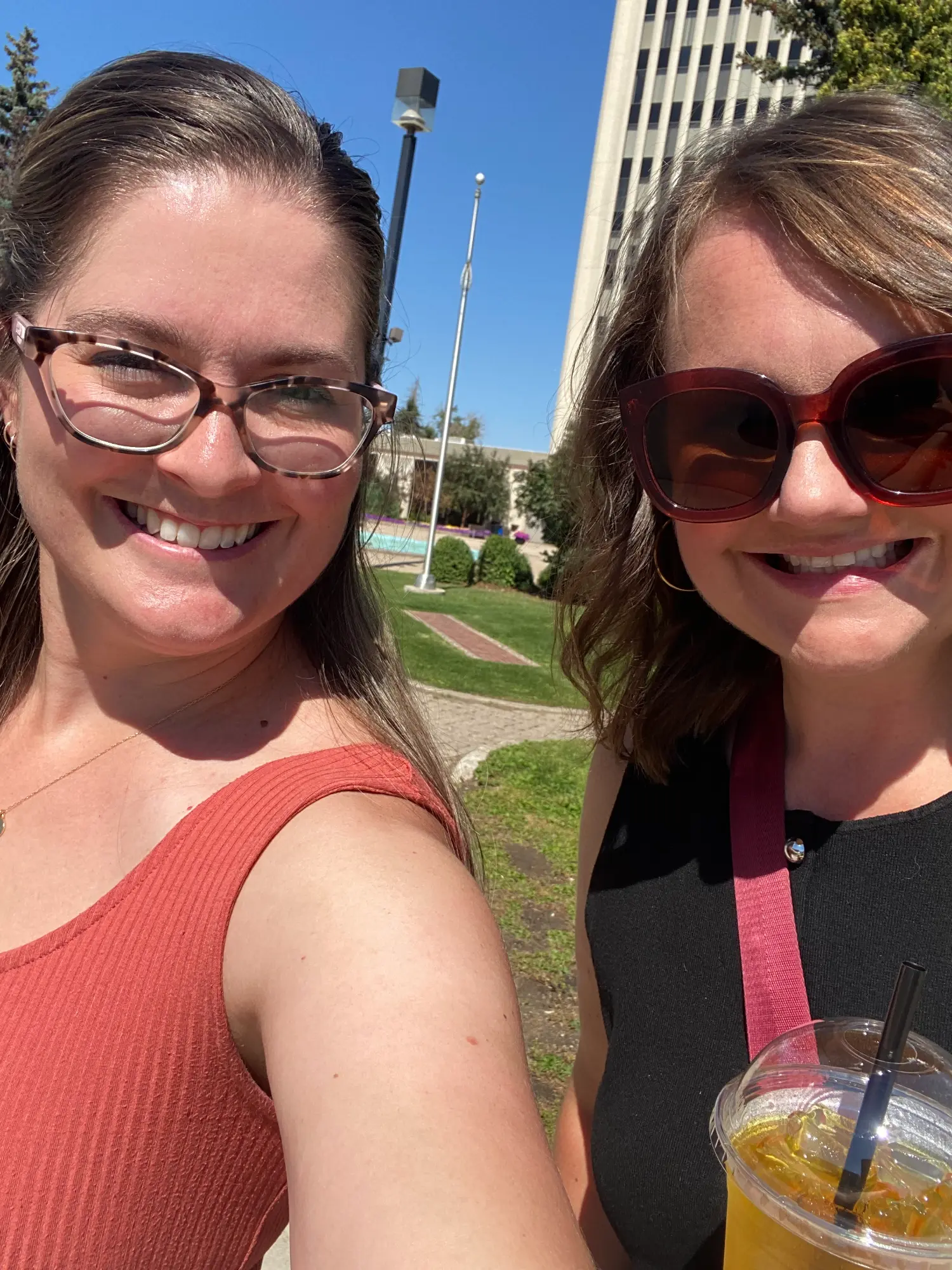 Two teammates strolling in the sun, sipping cool drinks, and stepping up for our summer walking challenge.