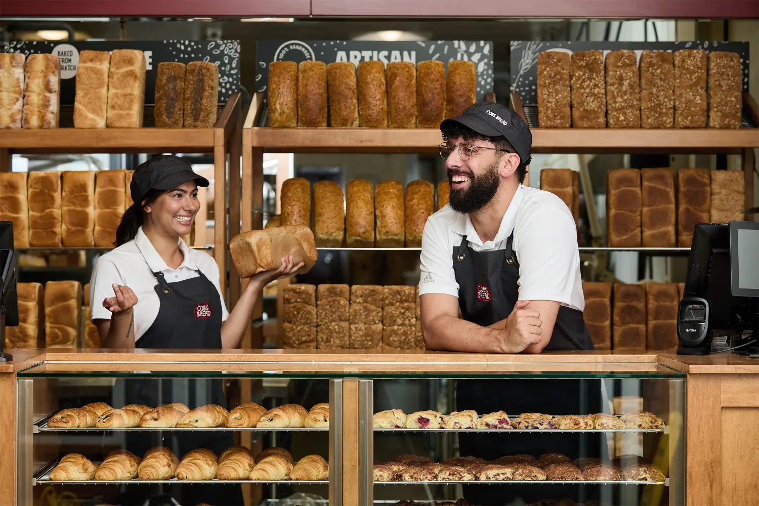 In front of an array of freshly baked bread, the sales staff wear big smiles, enjoying each other's company