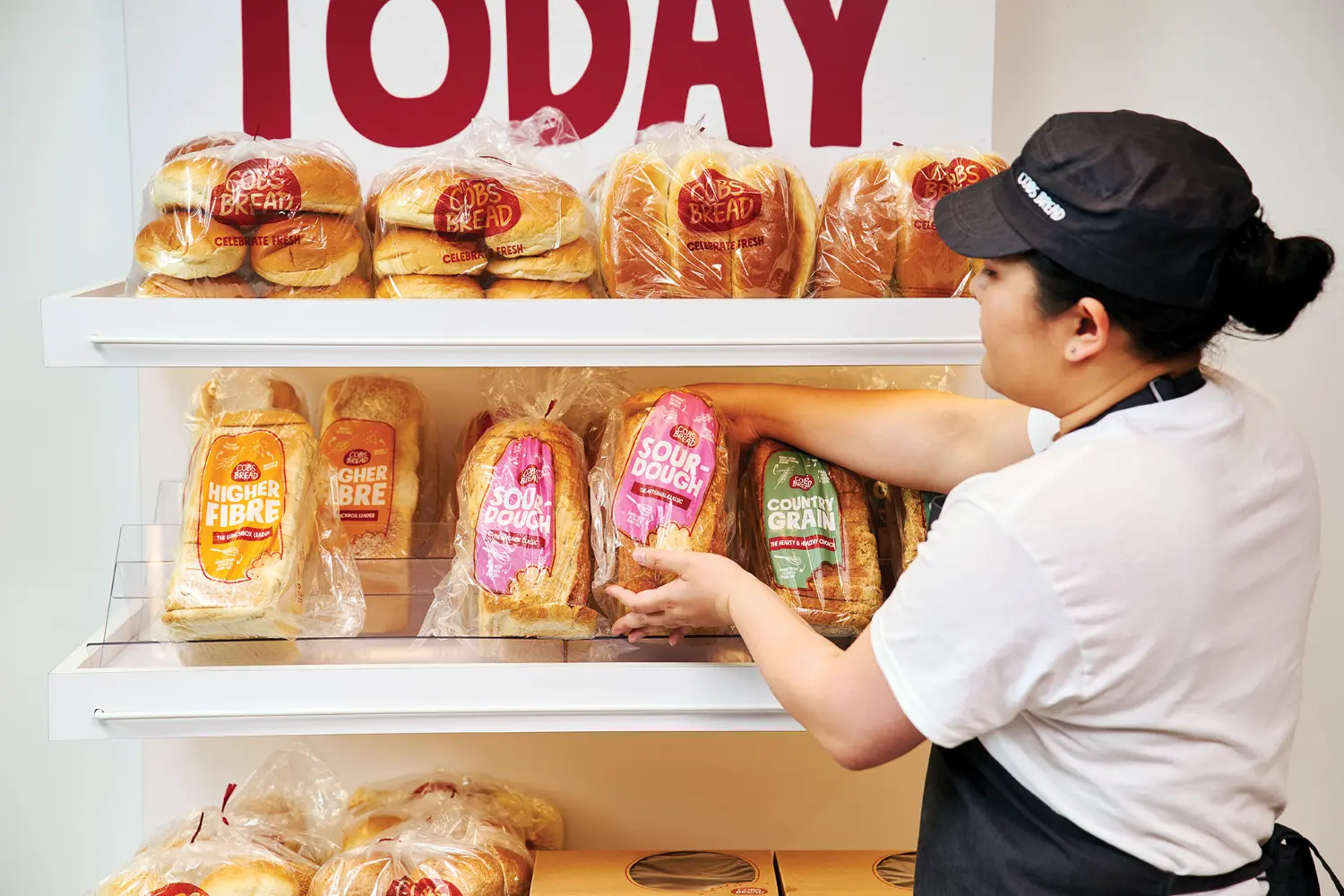 The sales associate nestles a golden loaf of sourdough onto the shelf for our customers.
