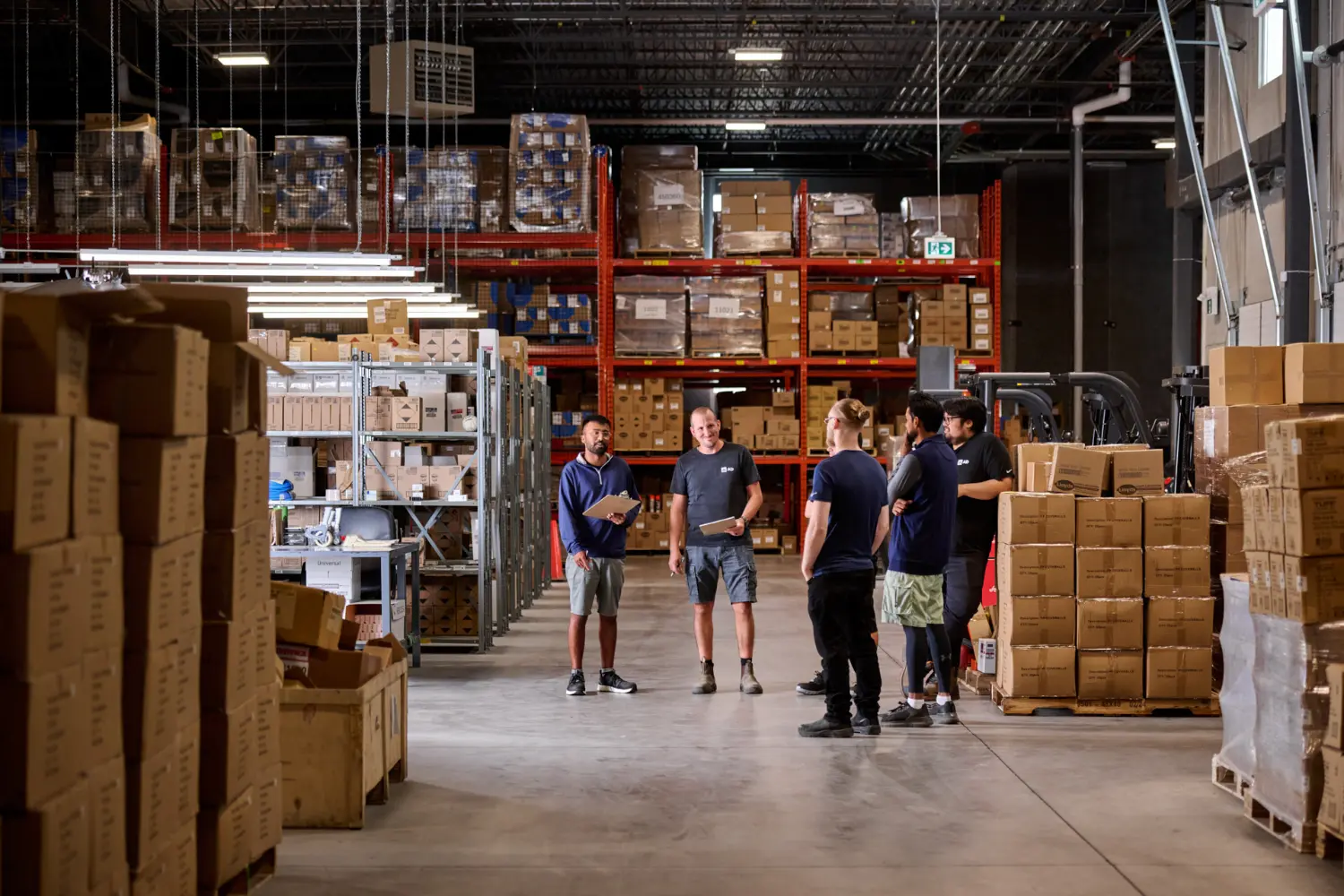 Team members discuss logistics and planning on the AD Canada Warehouse floor.