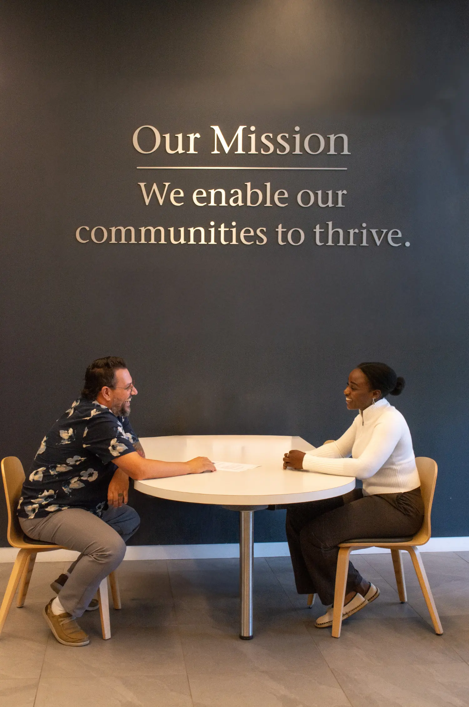 An employee assists a member under our ‘Our Mission’ sign, showing how we enable our communities to thrive.