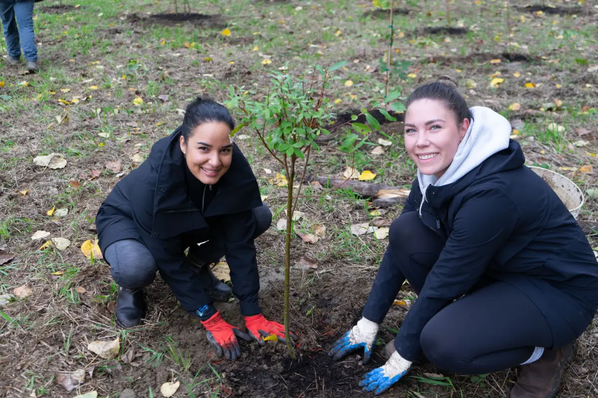 Kat and Mabel plant trees along the Fraser River to restore the local habitat.
