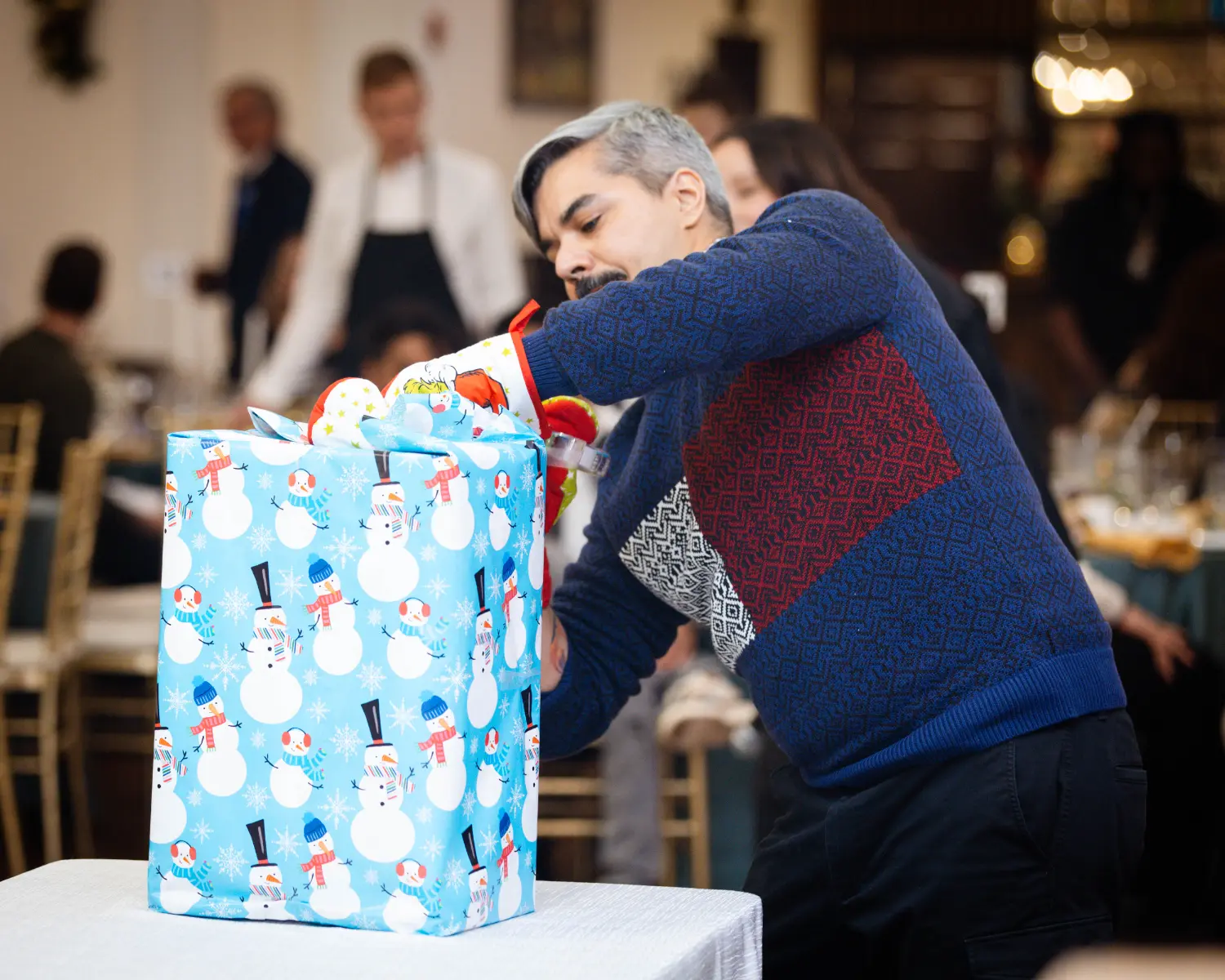 Team members enjoyed playing the oven mitt wrapping game at Tayco's 2025 Holiday Party