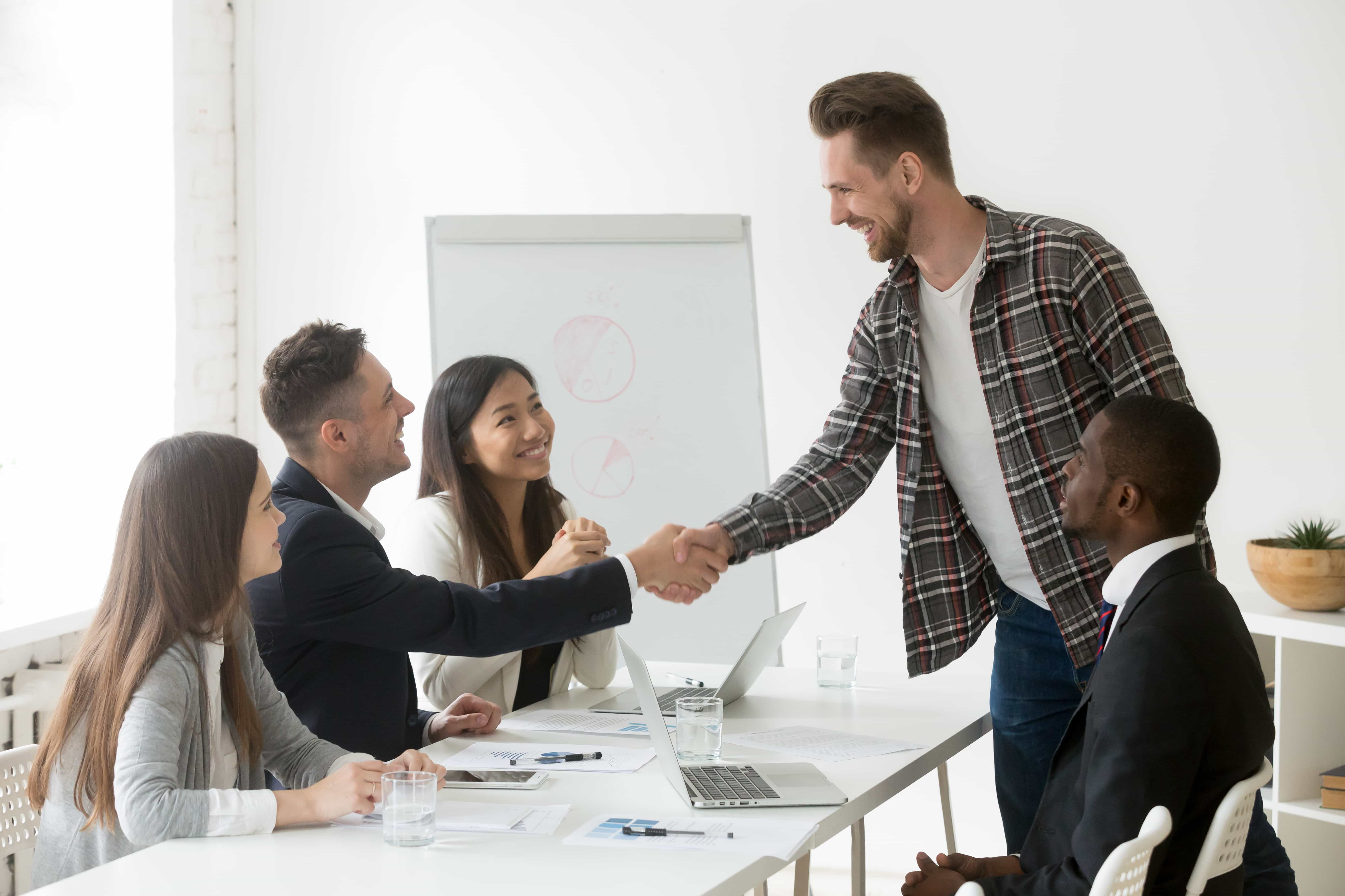 smiling businessman welcoming new partner group meeting with handshake 1